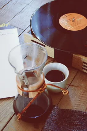 Glass pour-over kit beside a record player