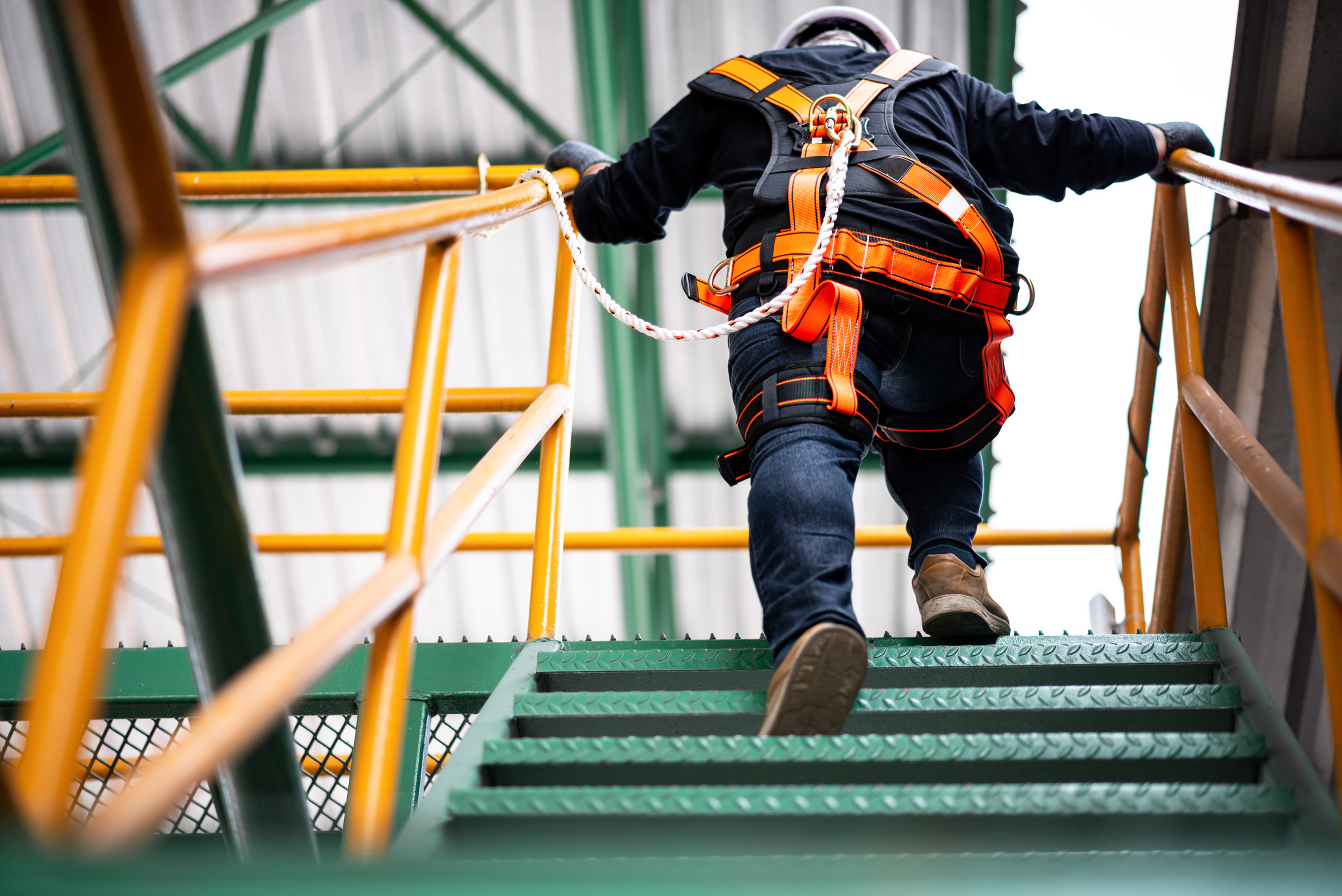 Worker in a safety harness climbing site stairs