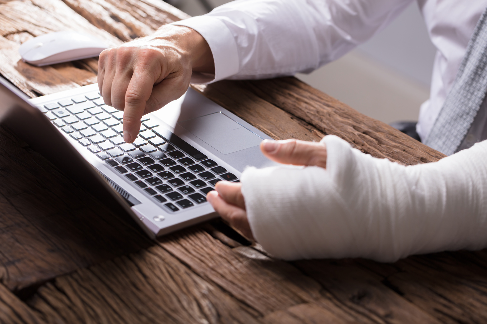 Injured worker with a bandaged hand at a laptop