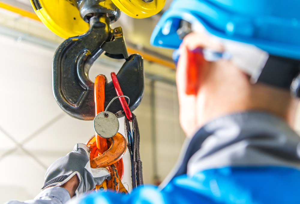 Worker inspecting a lifting hook and rigging