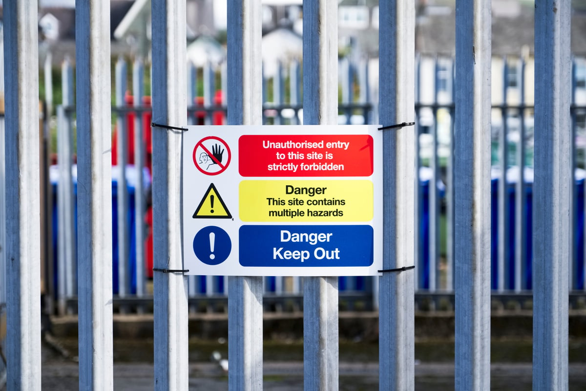 Danger chemical hazards keep out sign on fence no un authorised entry